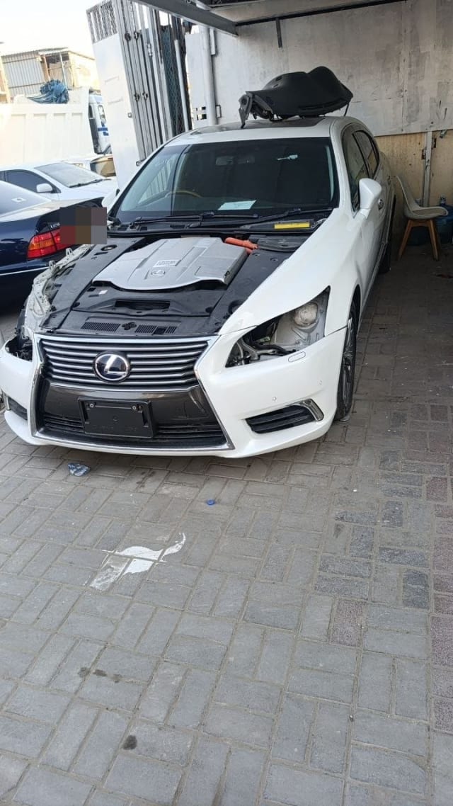 White Lexus LS460 sedan for parts — hood off, engine bay, spindle grille and front bumper, Sharjah market