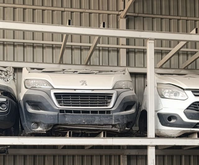 White Peugeot Boxer van front halfcut with bumper, grille and headlights on a rack, Sharjah market