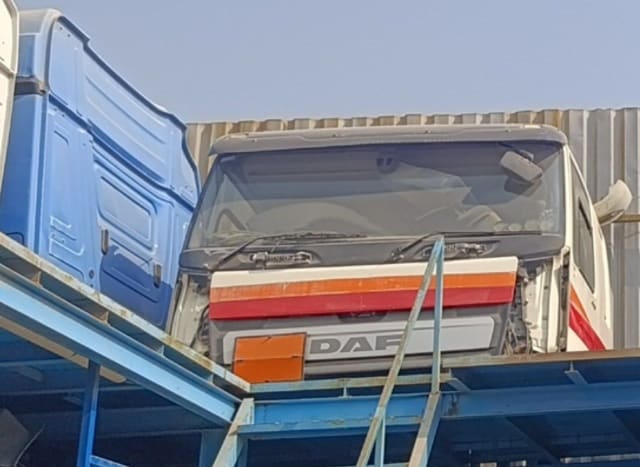 White DAF CF truck cab halfcut — windshield, striped front panel and DAF grille on a rack, Sharjah market