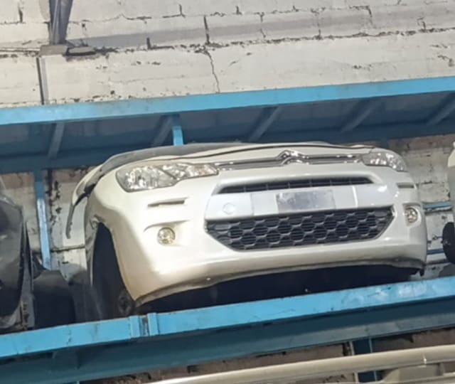 White Citroen C3 front halfcut on a rack: bumper, chrome grille, headlights and fog lights, Sharjah market