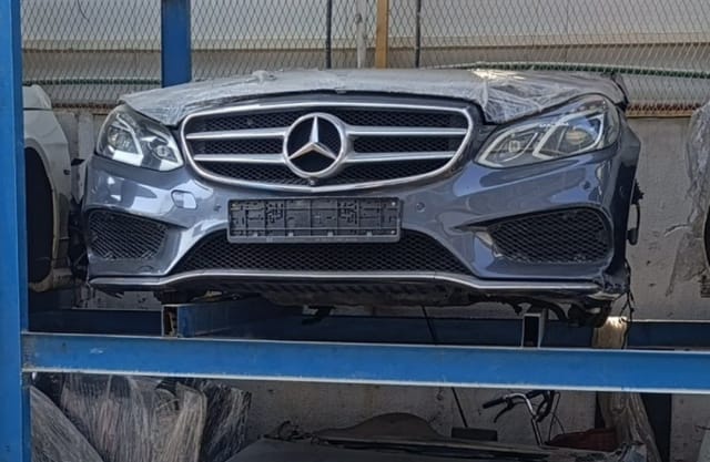 Grey Mercedes-Benz E-Class front halfcut with bumper, chrome grille and headlights on a rack, Sharjah market