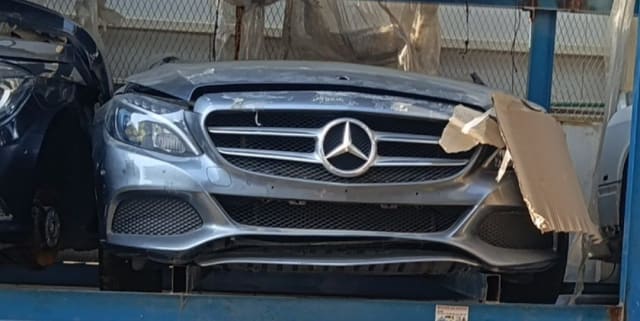 Silver-grey Mercedes-Benz C-Class front halfcut with bumper, grille, headlight and hood on a rack, Sharjah market