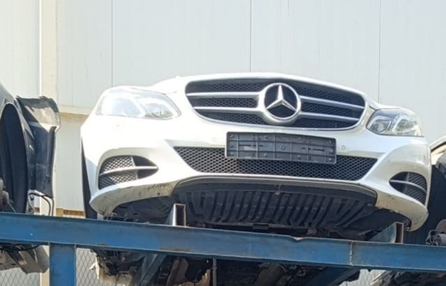 White Mercedes-Benz E-Class front halfcut with bumper, star grille and headlights on a rack, Sharjah market