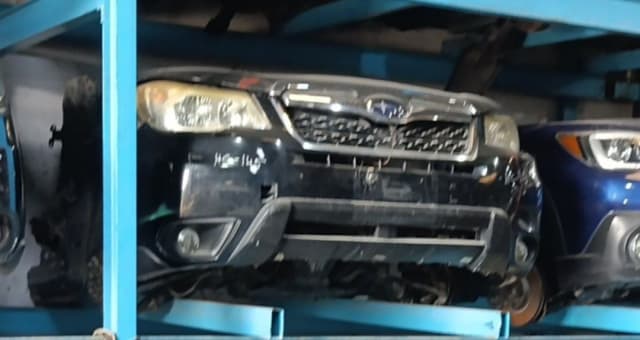 Black Subaru Forester halfcut on a blue rack: front bumper, grille and headlights, Sharjah market