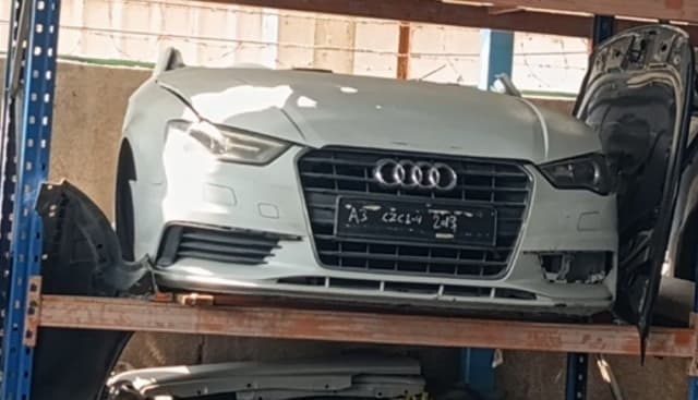White Audi A3 halfcut front section with hood, grille, bumper and headlights on a rack, Sharjah market
