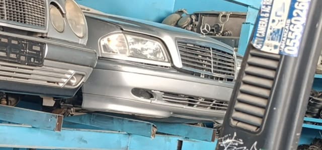 Grey Mercedes-Benz C-Class front halfcut with bumper, grille and headlights on a rack, Sharjah market