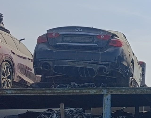 Black Infiniti Q50 sedan rear view: trunk lid, taillights, damaged rear bumper and exhaust tips, Sharjah market
