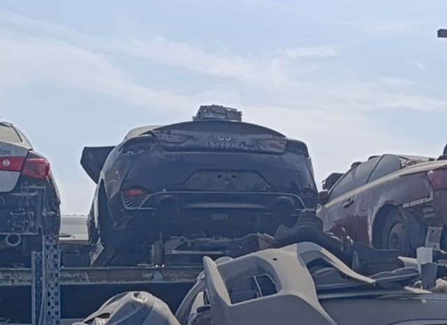 Dusty dark Infiniti Q60 coupe for parts, rear view of trunk lid, bumper and exhaust on a rack, Sharjah market