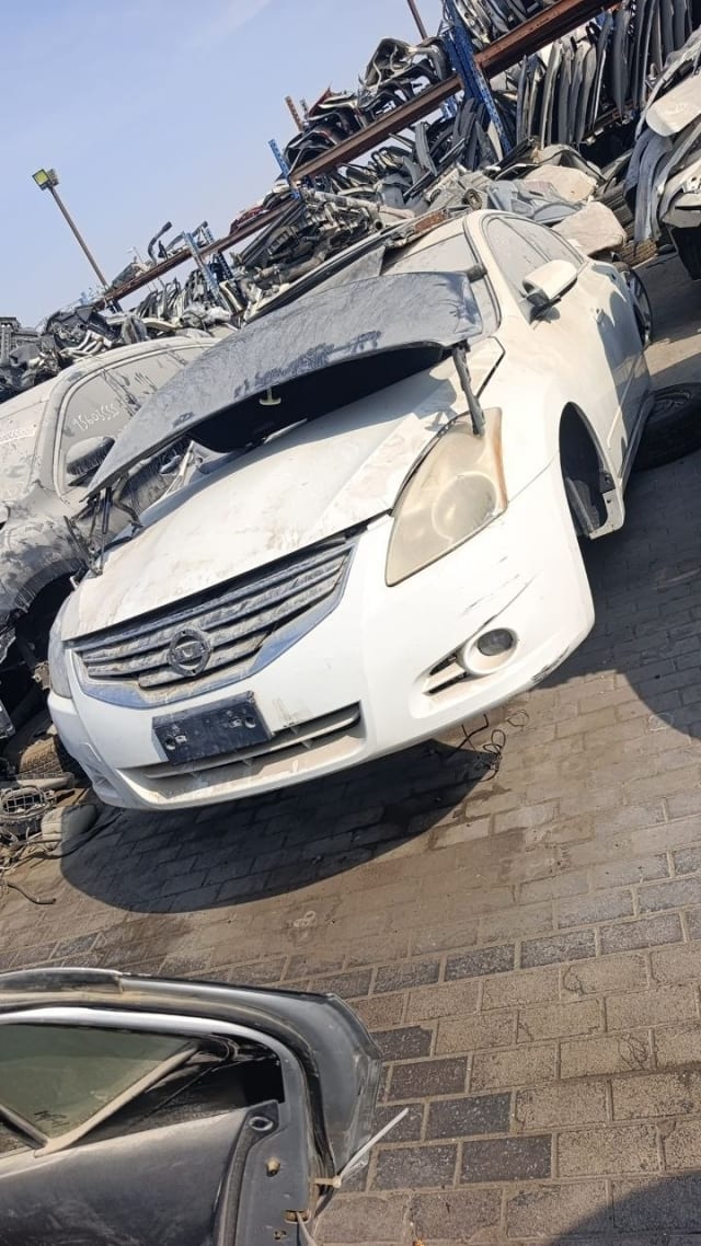 White Nissan Altima sedan for parts: grille, front bumper, headlight and open hood, Sharjah market