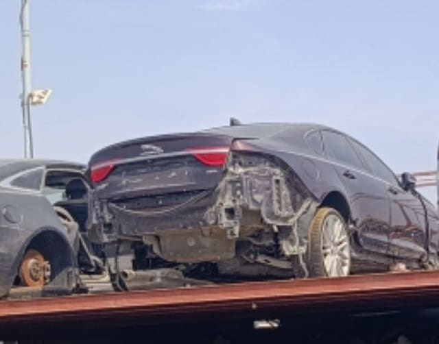 Dark Jaguar XF sedan for parts on flatbed — trunk lid, taillights, doors, alloy wheel, Sharjah market