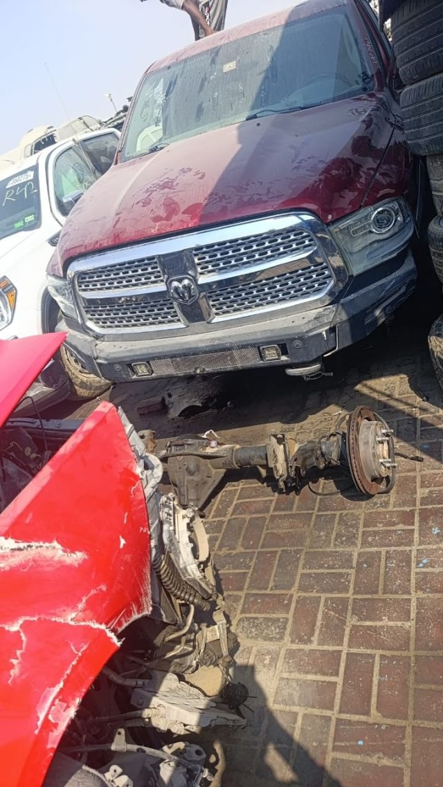 Dark red RAM 1500 pickup for parts — chrome grille, headlights, hood and loose front axle, Sharjah market