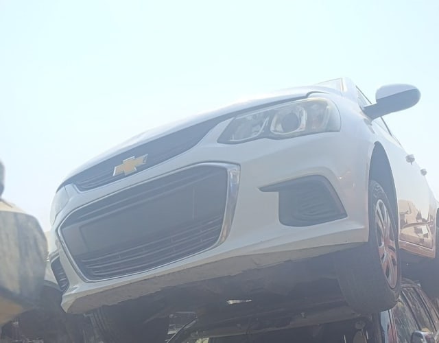 White Chevrolet Sonic sedan for parts — front bumper, grille, headlight and hood, Sharjah market