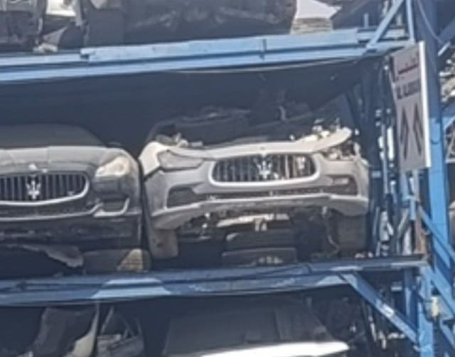 Grey Maserati Ghibli halfcut front with bumper and trident grille on a steel rack, Sharjah market