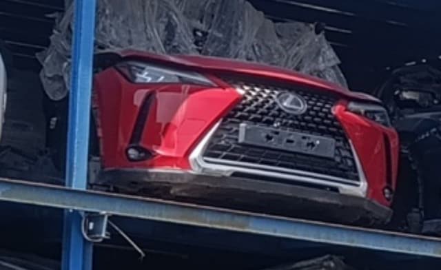 Red Lexus UX front halfcut with spindle grille, bumper and headlights on a rack, Sharjah market