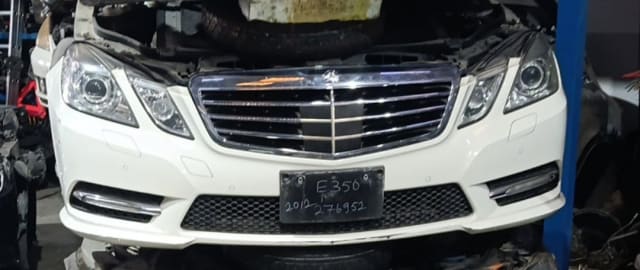 White Mercedes-Benz E-Class front halfcut with chrome grille, headlights and bumper, Sharjah market
