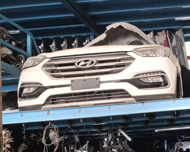 White Hyundai Santa Fe front halfcut with bumper, grille, headlights and fog lights on a rack, Sharjah market
