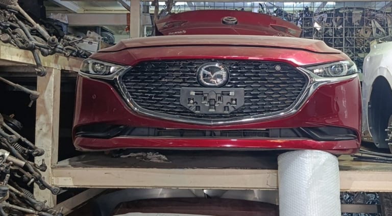Red Mazda3 sedan front cut — bumper, mesh grille, headlights and hood, Sharjah market