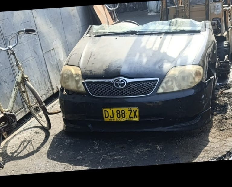 Black Toyota Corolla sedan front halfcut — bumper, chrome grille and headlights, Sharjah market
