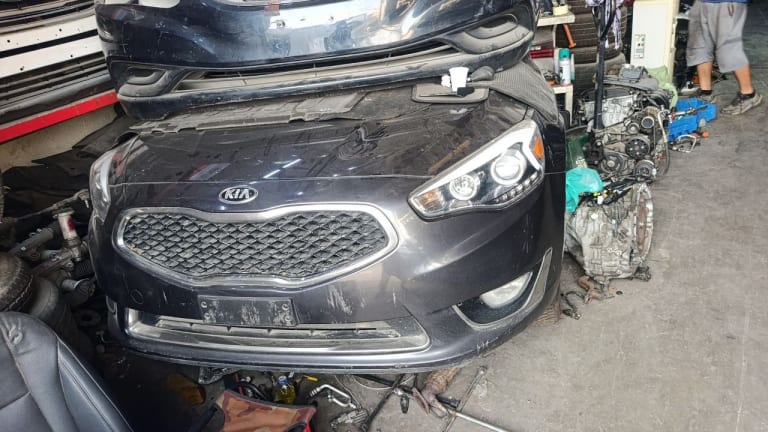 Dark grey Kia Cadenza sedan front halfcut — bumper, grille and headlights, Sharjah market