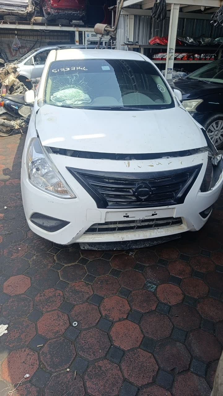 White Nissan Sunny sedan front — bumper, grille, headlights and hood, cracked windshield, Sharjah market
