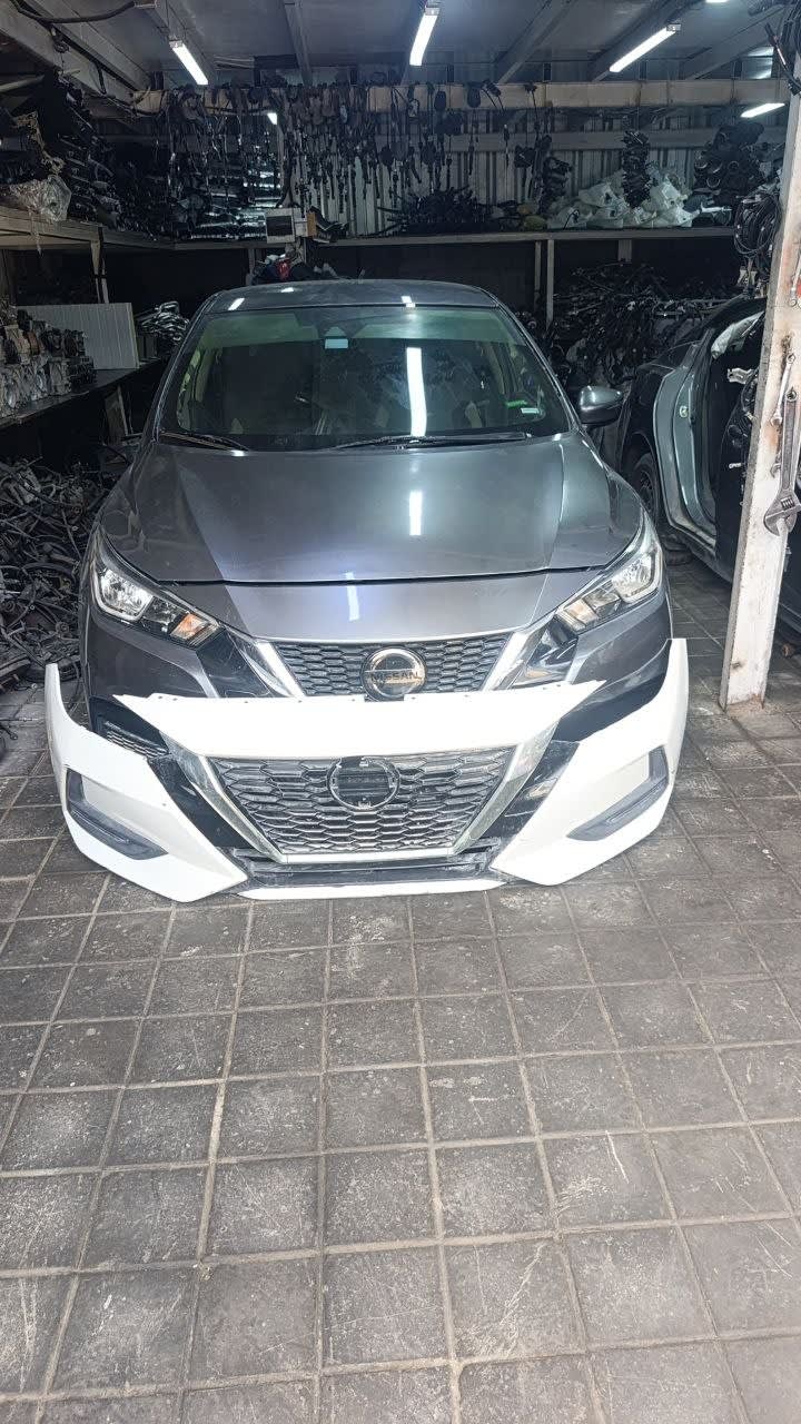 Grey Nissan Sunny sedan front halfcut — hood, headlights, grille and white front bumper, Sharjah market