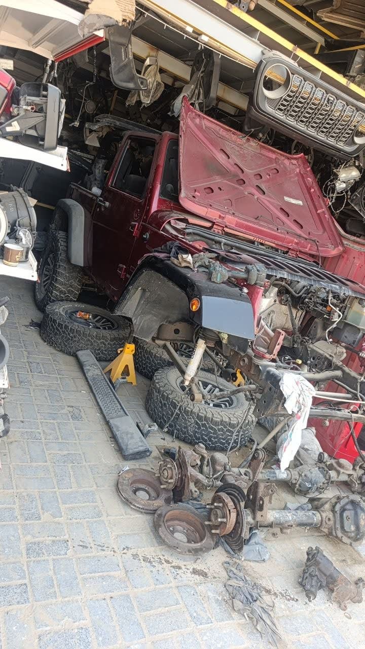 Dark red Jeep Wrangler SUV halfcut — hood, fenders, wheels and suspension parts, Sharjah market