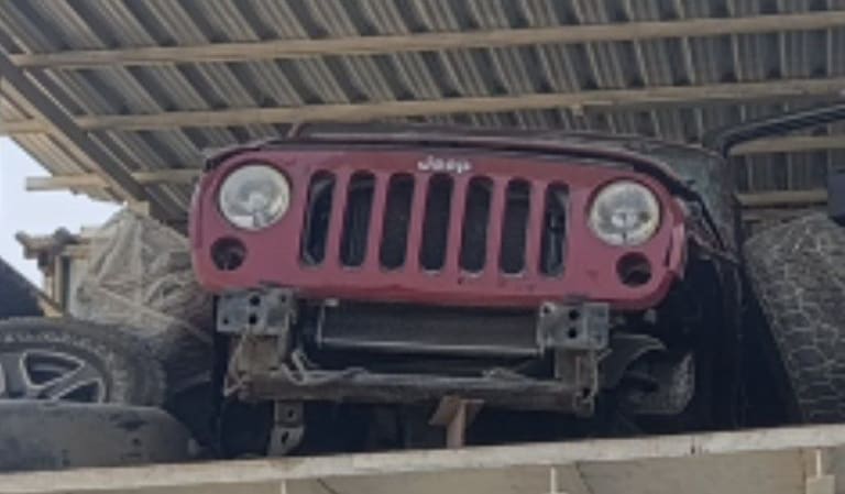 Red Jeep Wrangler front cut — seven-slot grille, round headlights and radiator support, Sharjah market