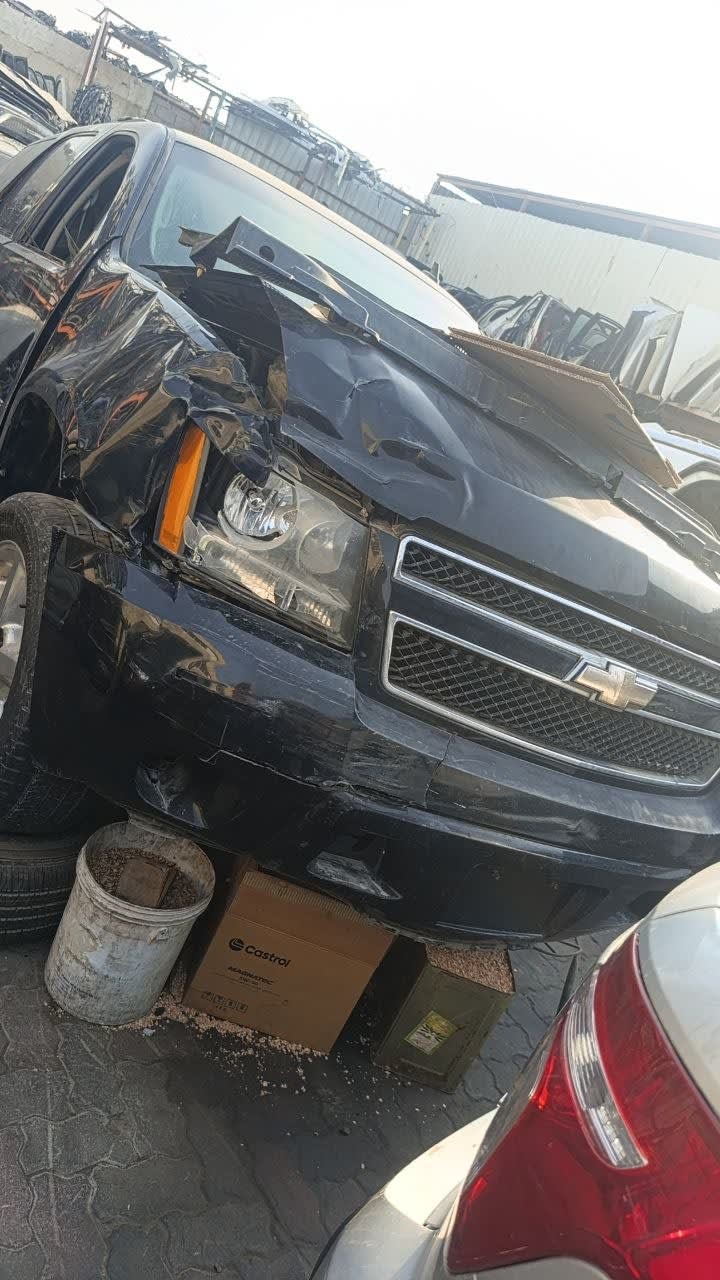 Black Chevrolet Tahoe SUV front halfcut — grille, headlights and bumper with front-end damage, Sharjah market