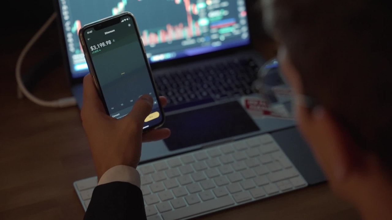 Coverr a Trader Performing Financial Analysis of Cryptocurrency Using a Phone App and Laptop preview