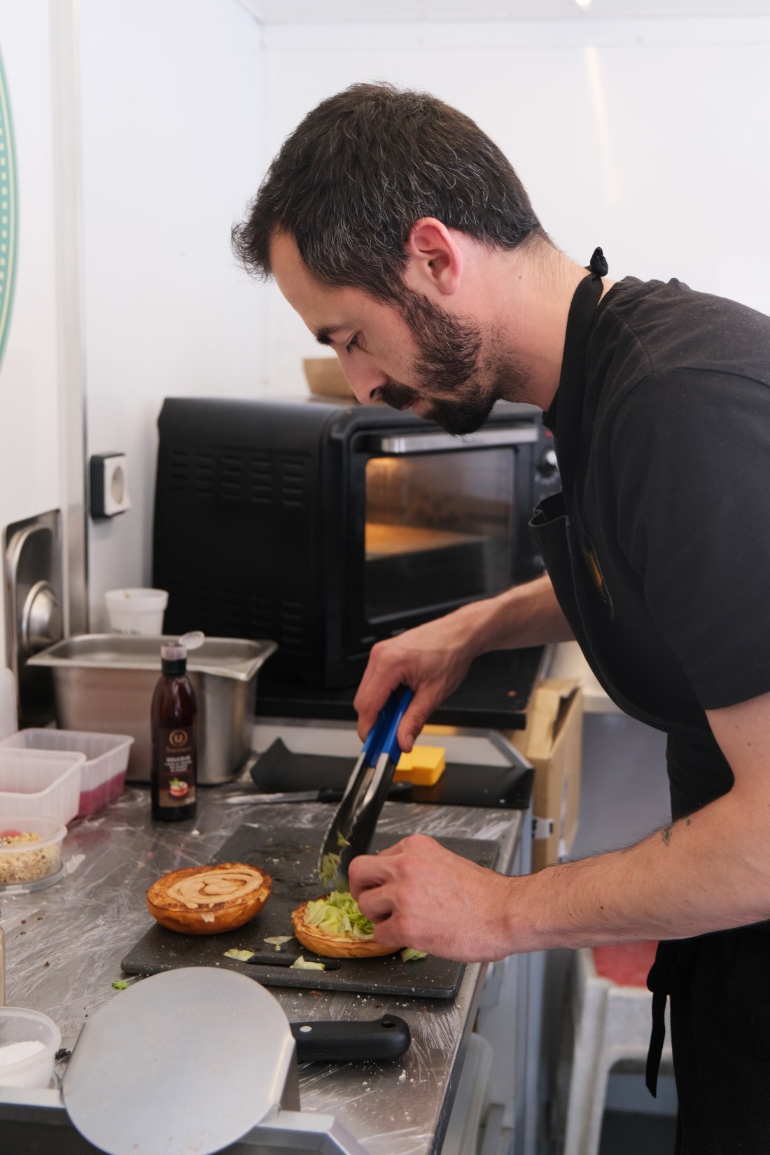 Paul de La Bolinette en cuisine, en train de dresser un sandwich toasté ouvert sur planche en pierre