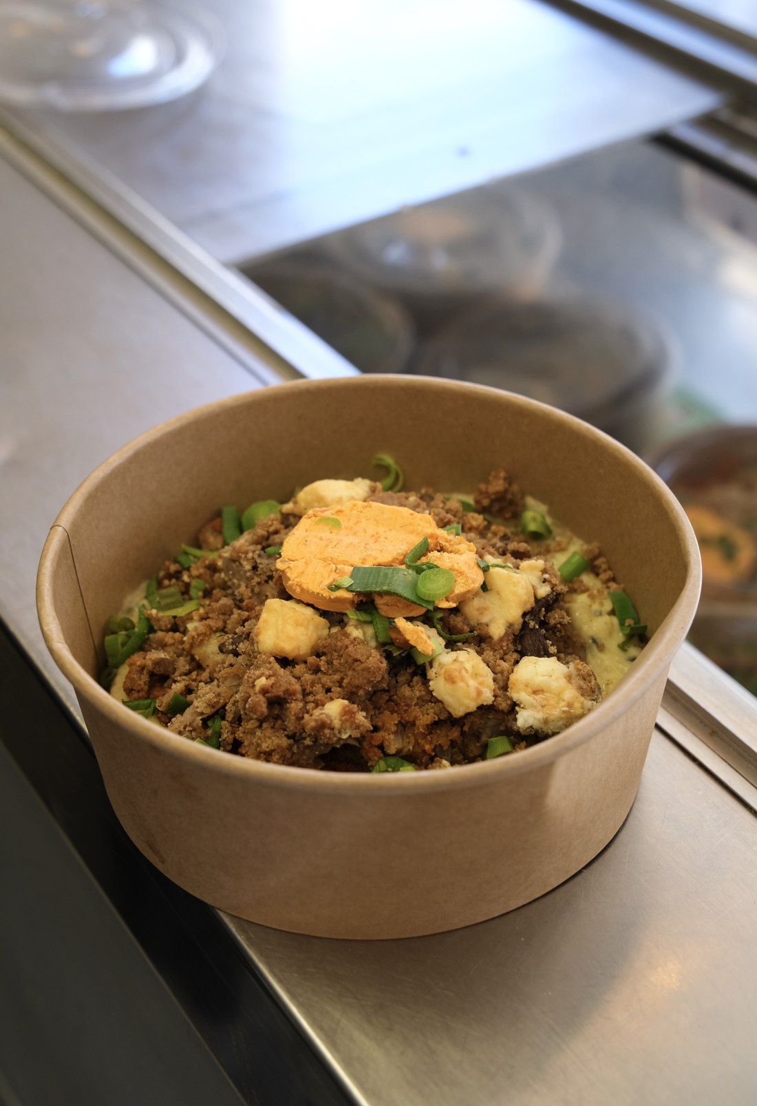 Un bowl signature de La Gamelle : céréales, viande hachée croustillante, légumes croquants, œuf, ciboule fraîche en barquette kraft