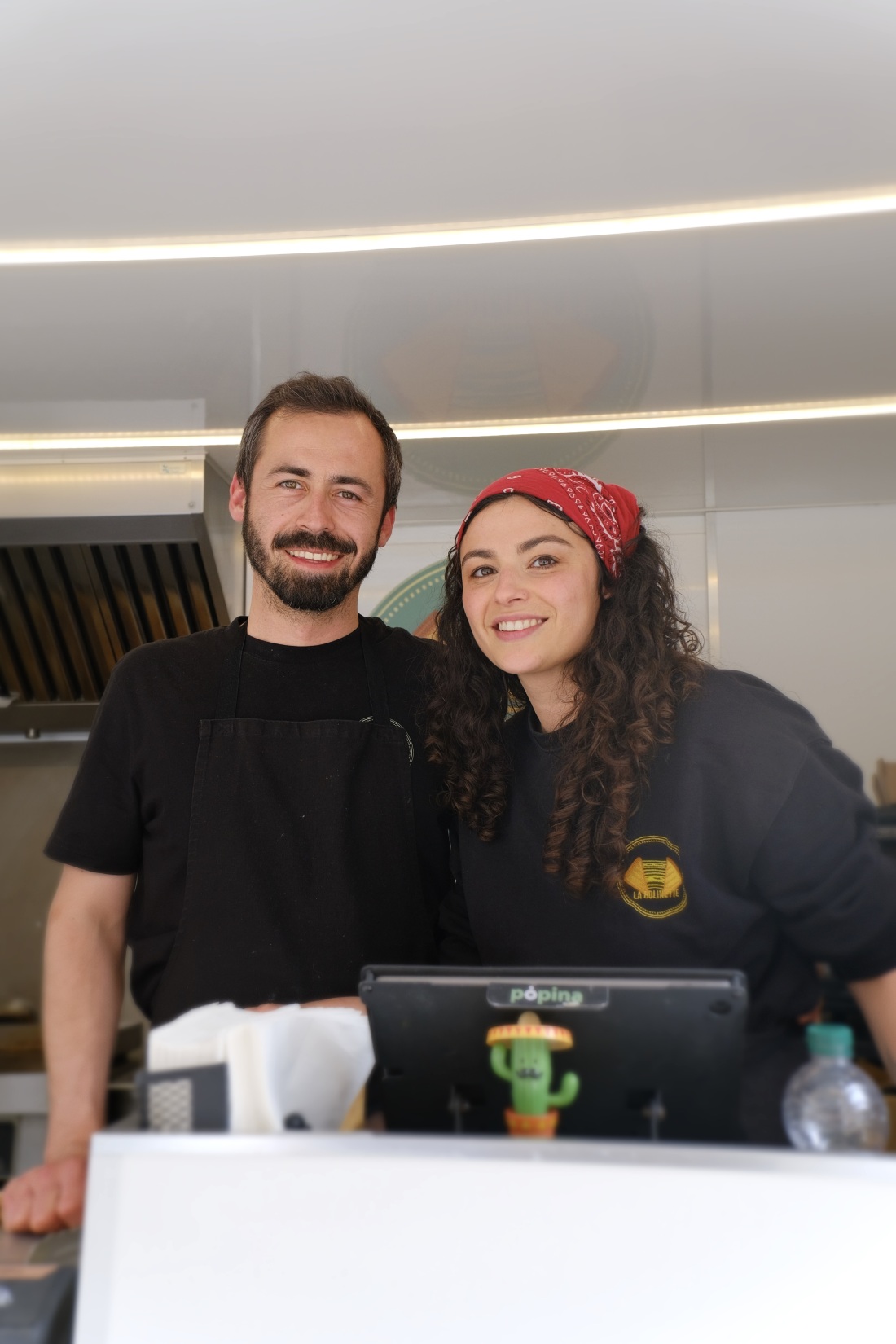 Alexandrine et Paul, le couple derrière La Bolinette, côte à côte derrière le comptoir de leur food truck vert