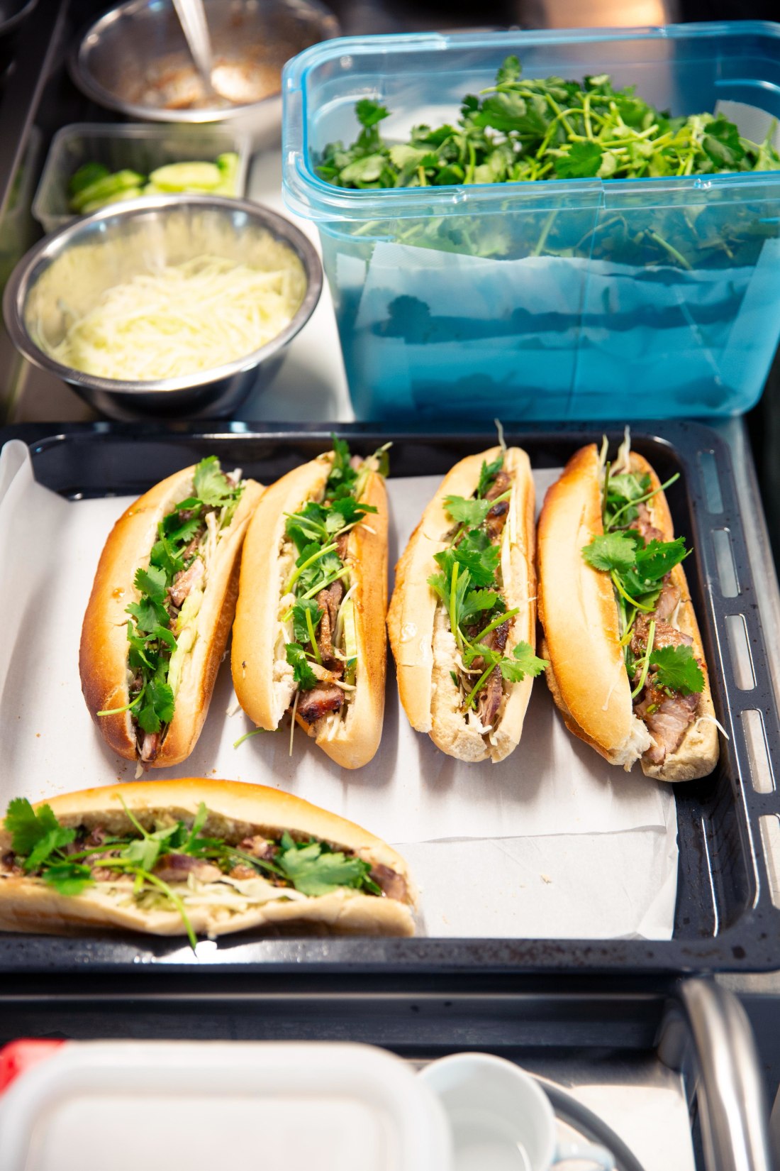 Plateau de bánh mì Banh Banh fraîchement montés, garnis de coriandre fraîche, dans le laboratoire du food truck