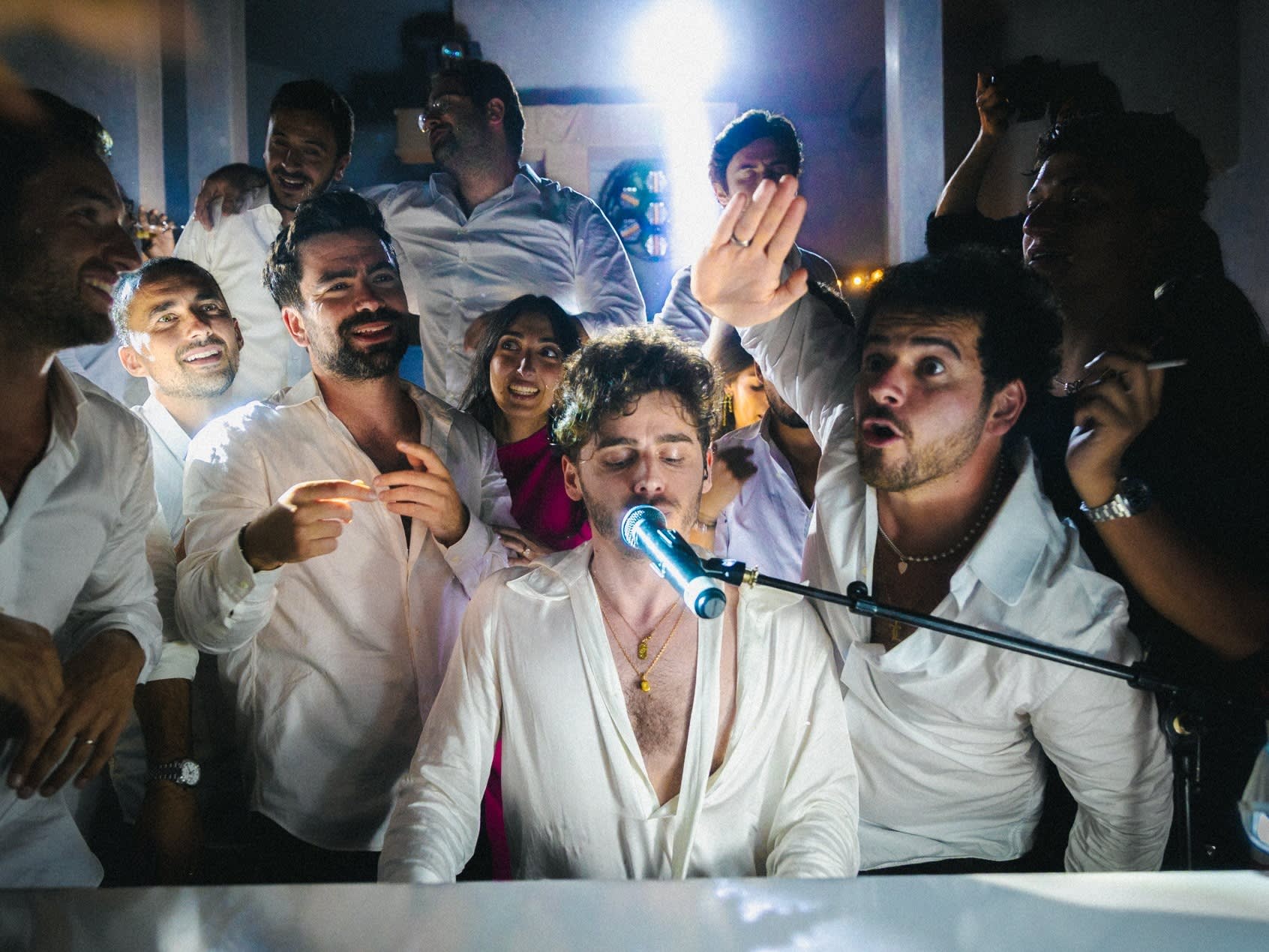 Musicien chanteur entouré des invités sur la piste de danse en soirée, groupe de musique vs DJ