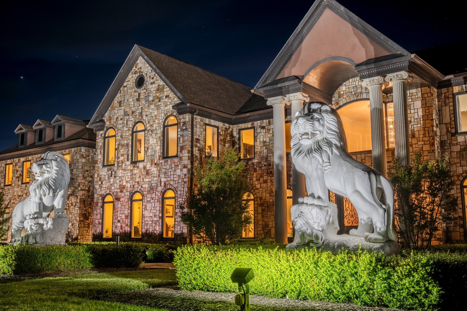 Nighttime exterior shot of The Inn at Grass Roots Hill in Purcellville VA featuring marble lion statues at luxury estate — real estate photography