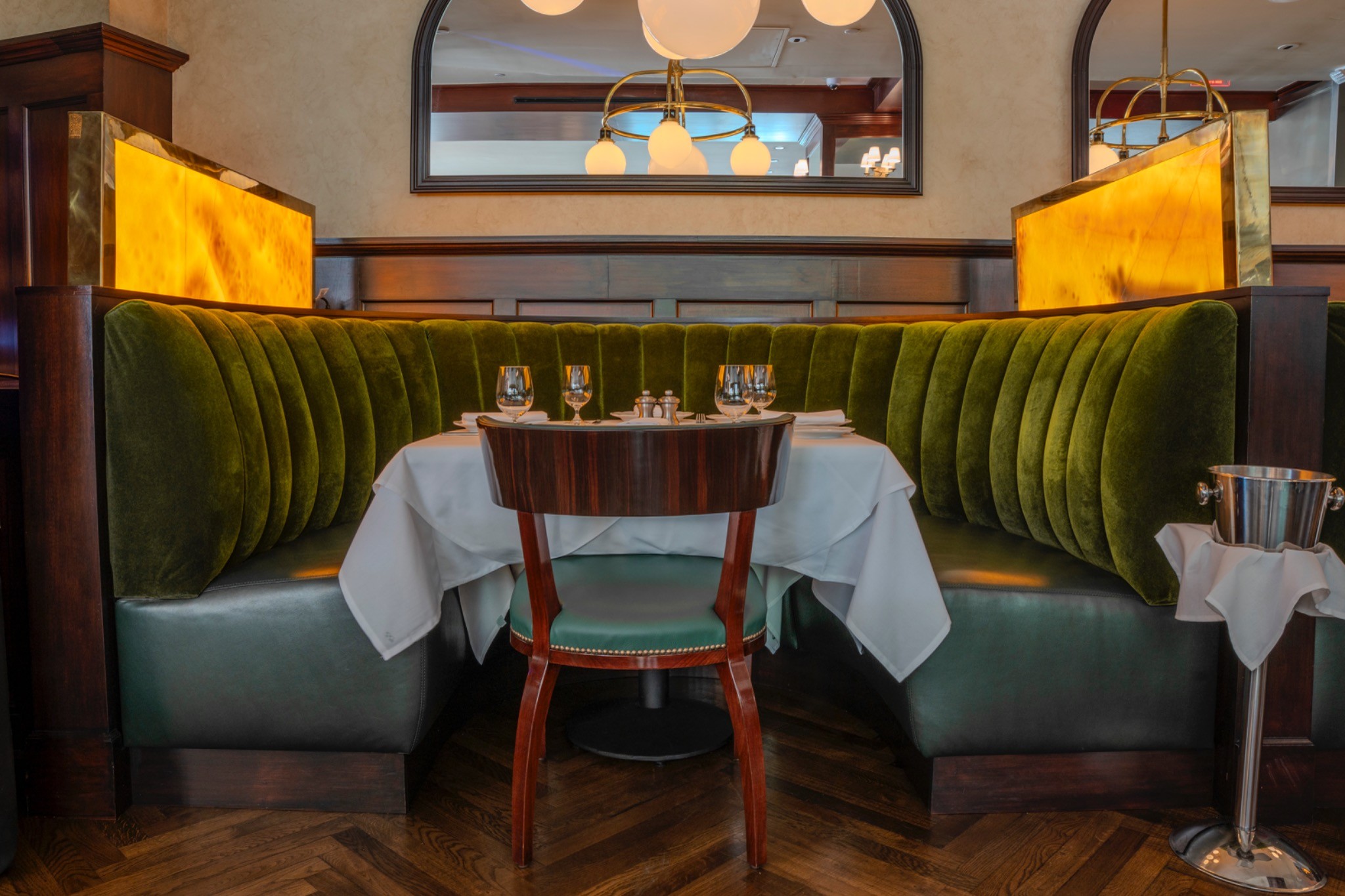 Custom upholstered emerald green booths and backlit onyx partitions at Café Fiorello DC — high-end restaurant interior photography