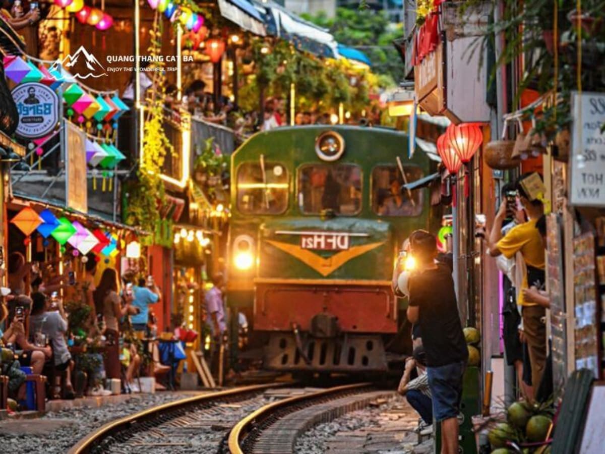 Train passing through Train Street Hanoi with cafés on both sides