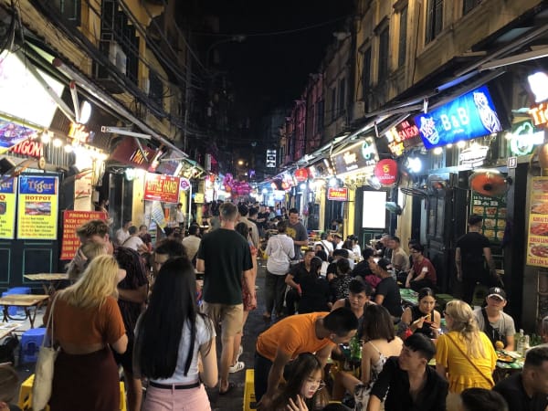 Street in Hanoi Old Quarter at night with neon signs and people