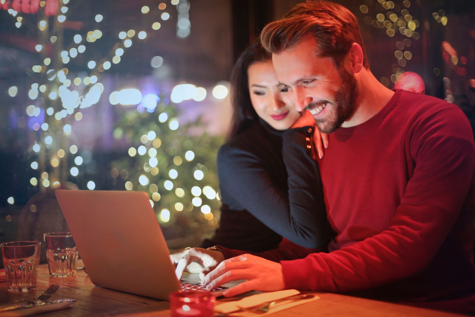 A man and a woman smiling whilst looking at a laptop
