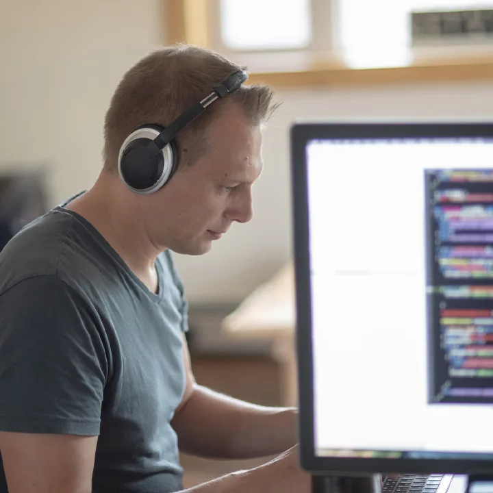 Herr mit Kopfhörern, der an einem Computer arbeitet