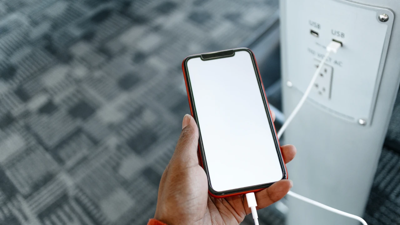 Traveler using phone while charging at MIA Airport