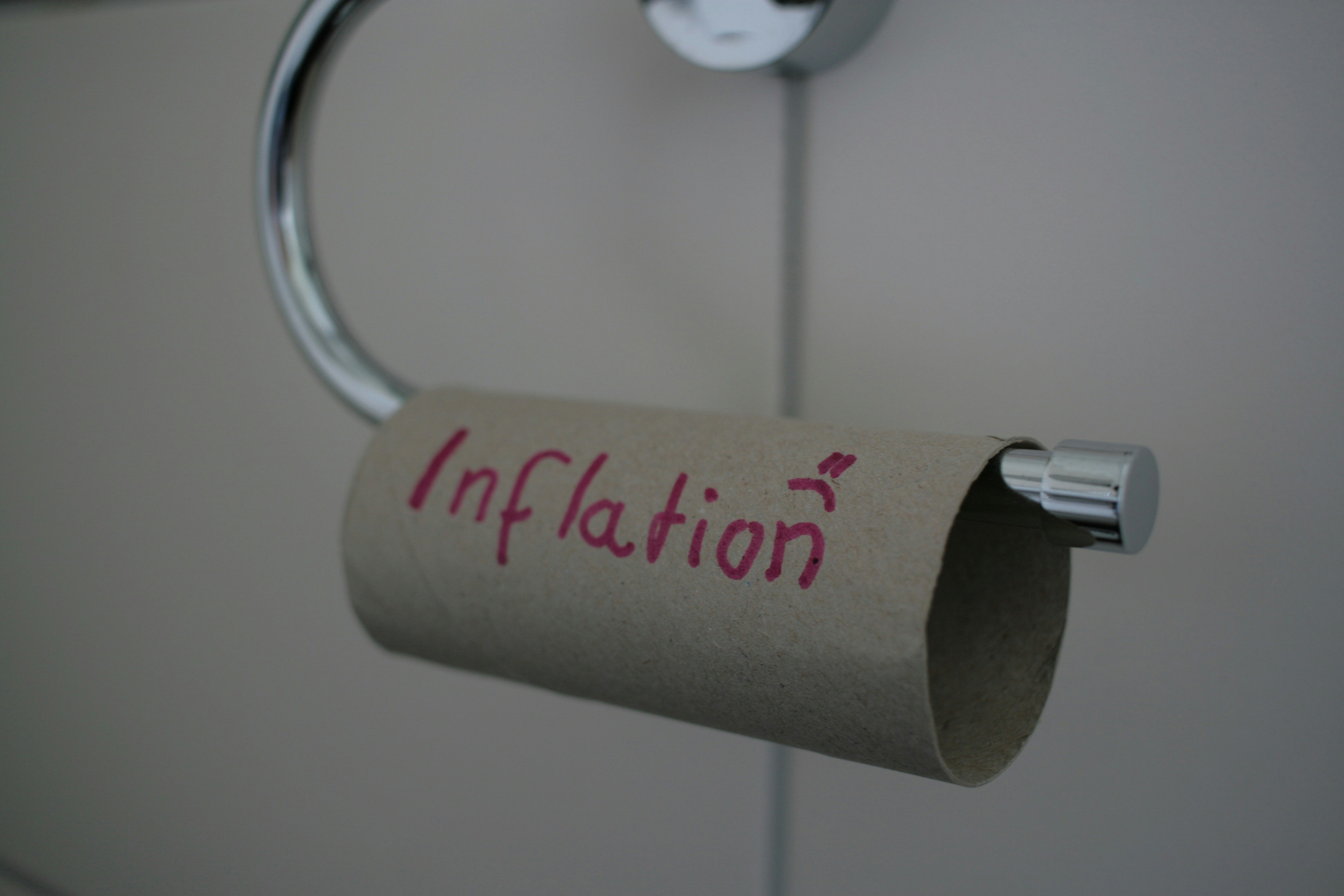 an empty toilet paper roll with the word "inflation" written on it and a frowny face