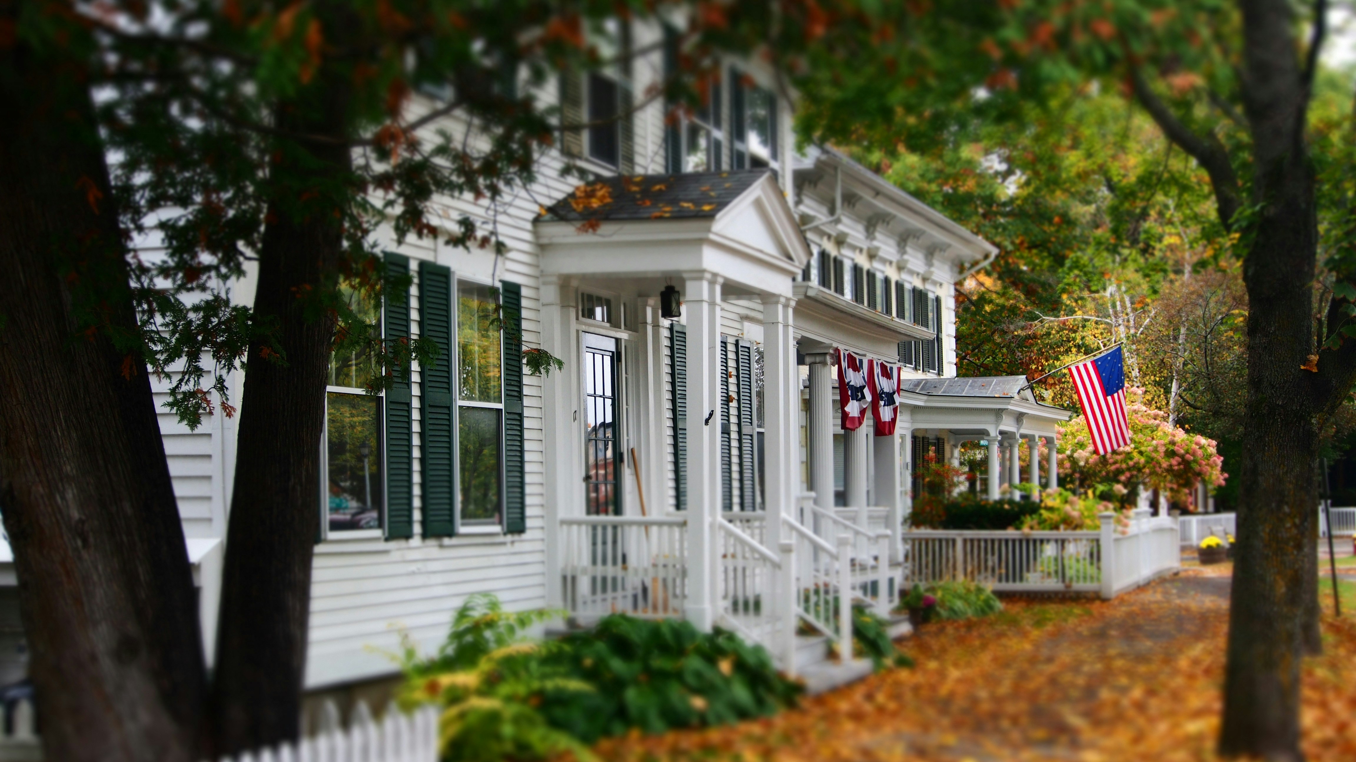 Classic New England home surrounded by bright orange fall foliage