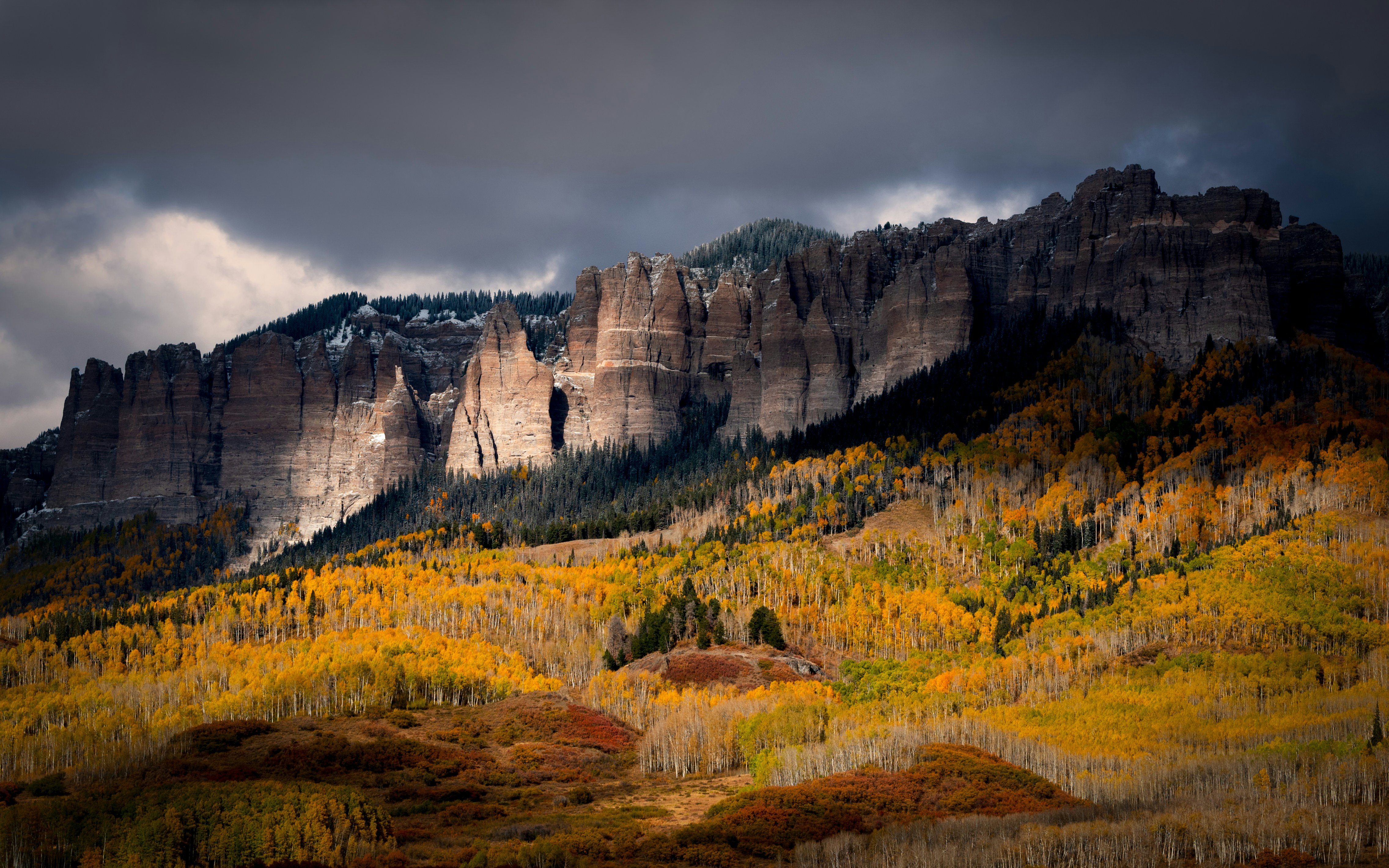 A steep rockface in Ridgeway, Colorado, surrounded by trees with bright yellow leaves