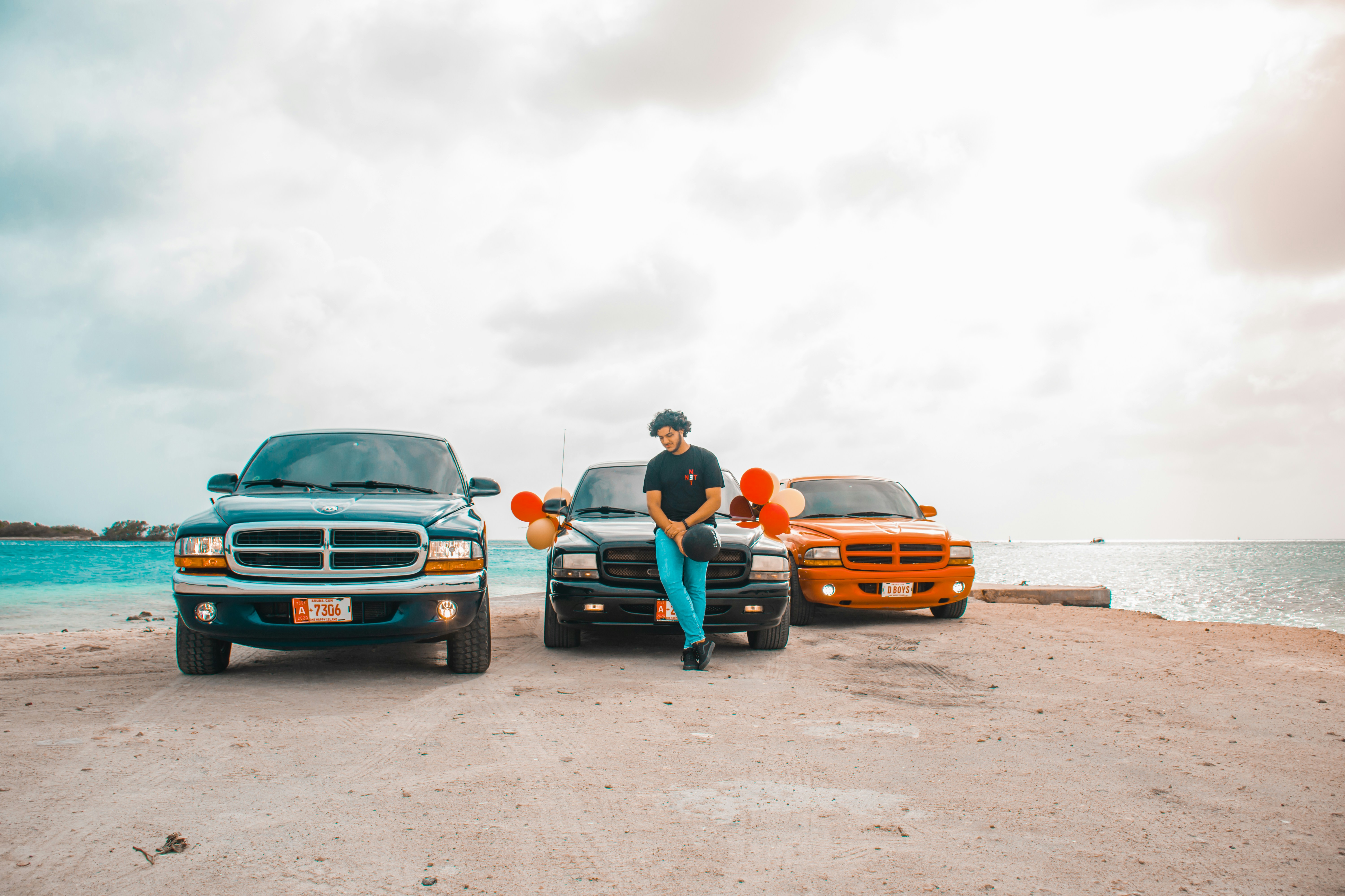 man leaning on truck with balloons in row of three trucks