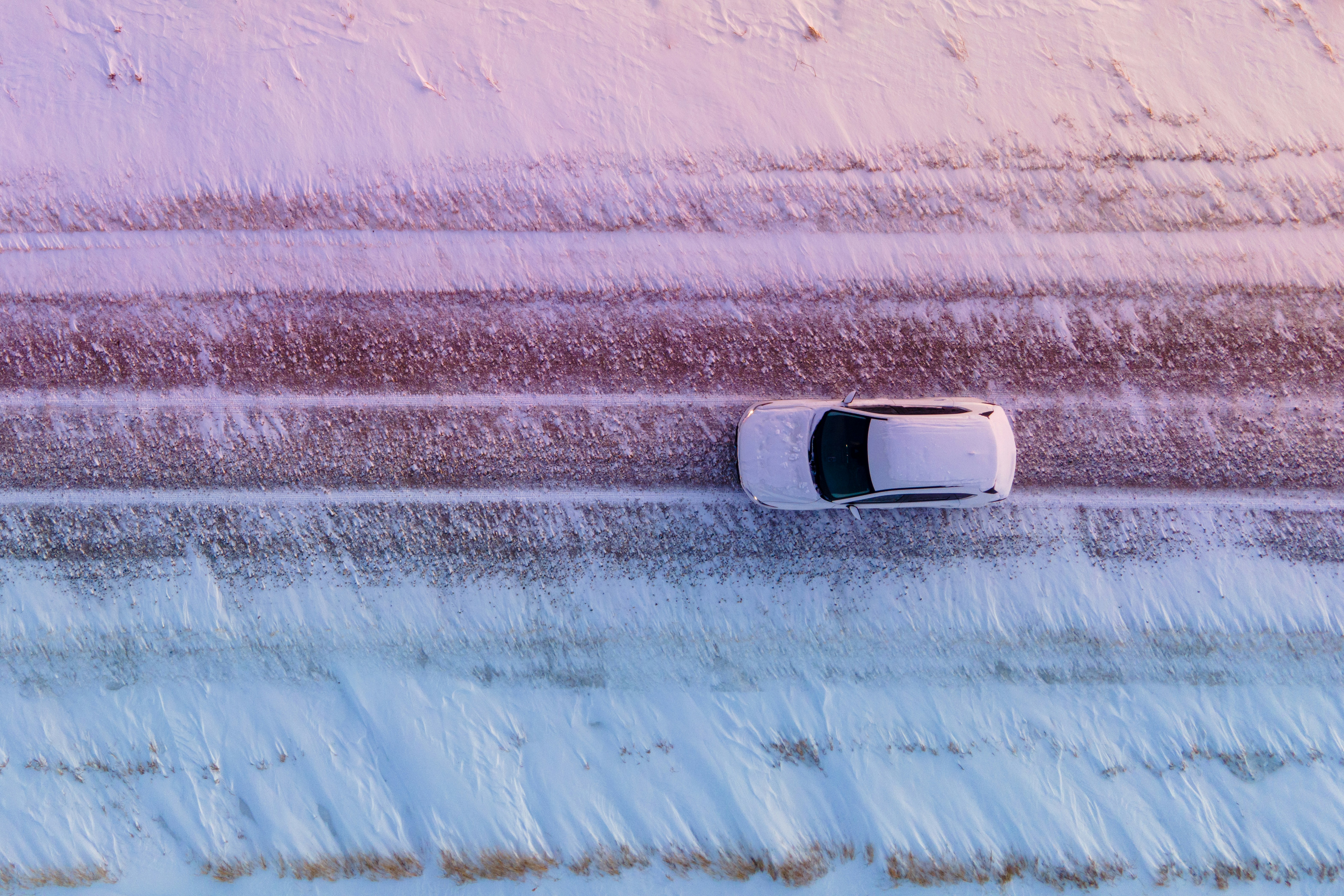 white car driving on snowy road, pictured from above