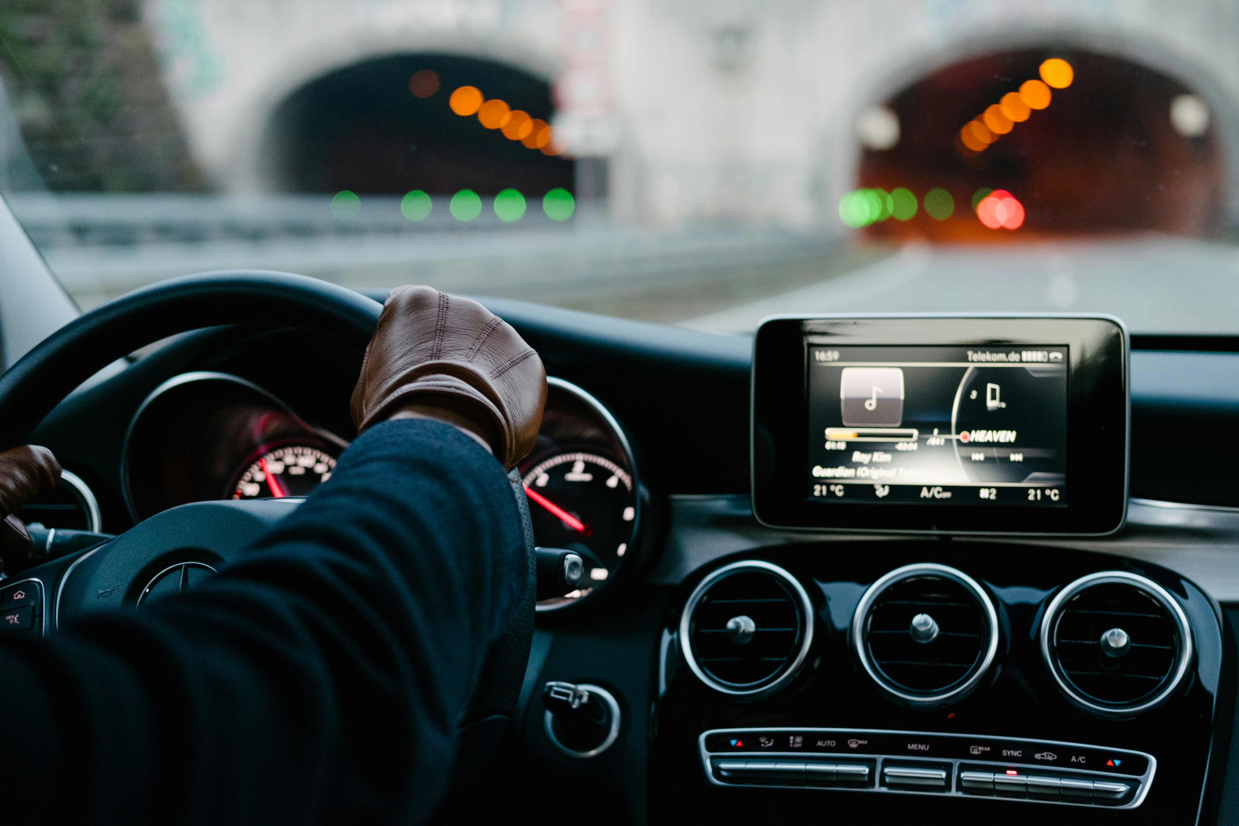 gloved hand on steering wheel, driving into tunnel