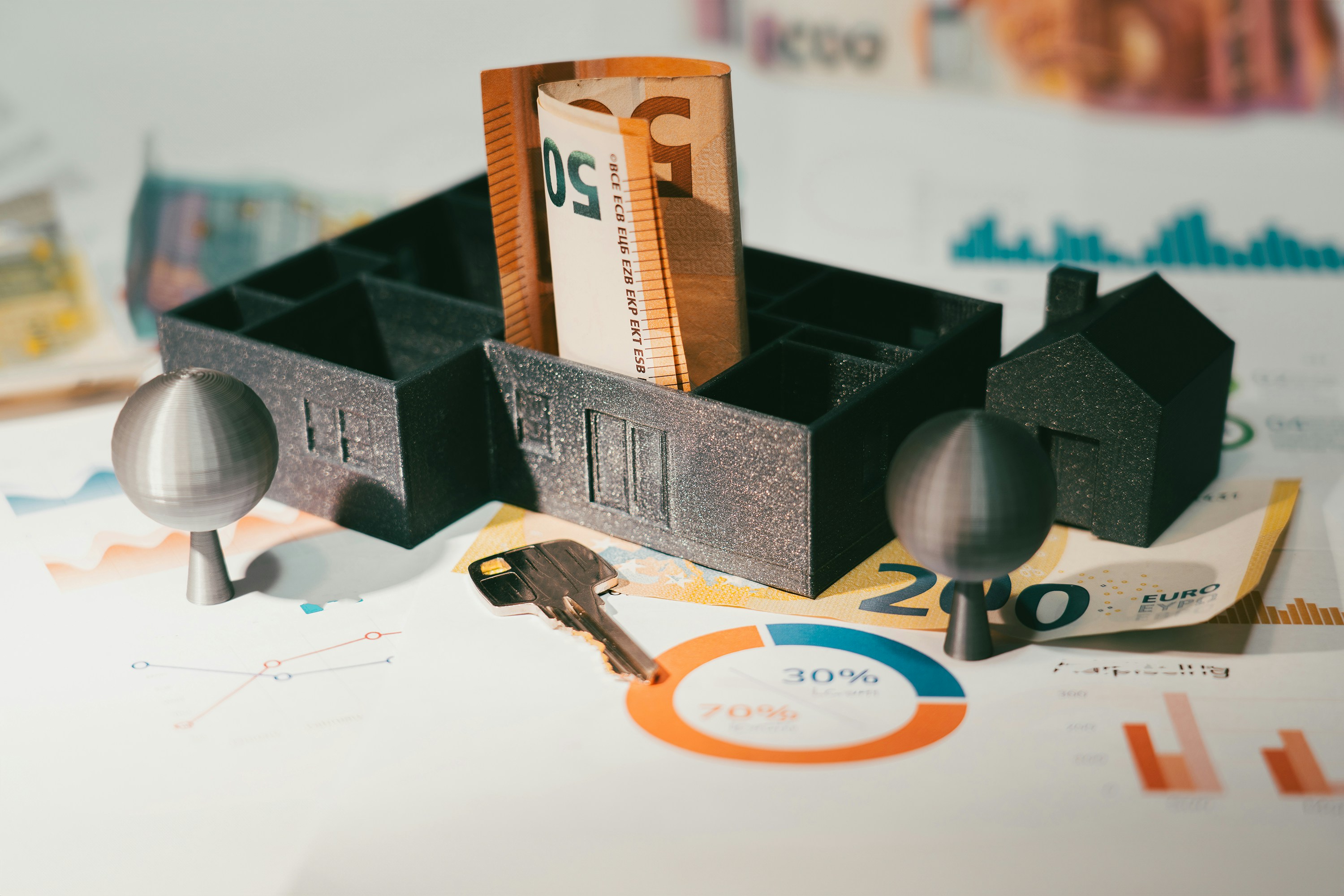 close up of various trinkets: money, keys, charts, toy house and trees