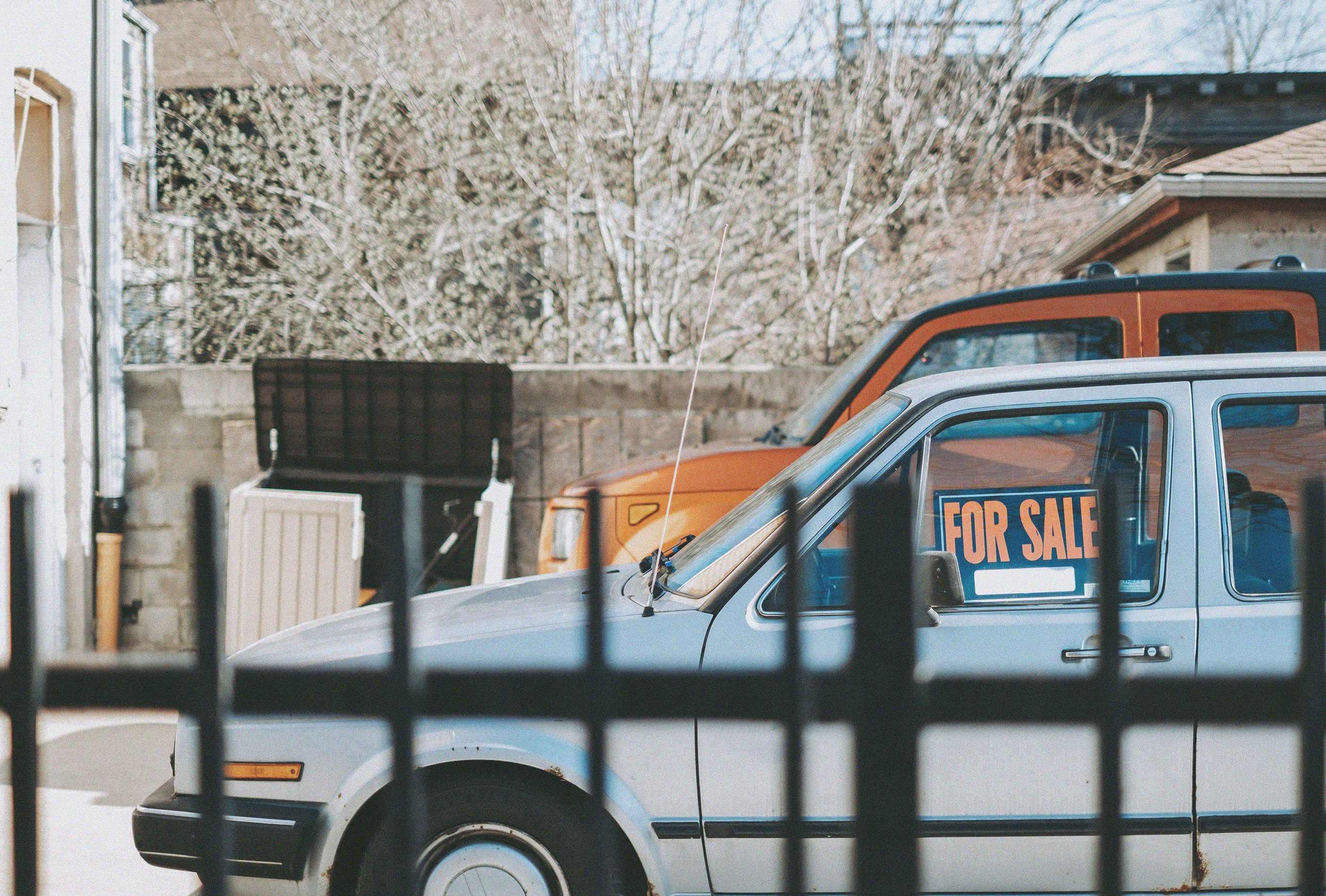 grey parked sedan with for sale sign in window