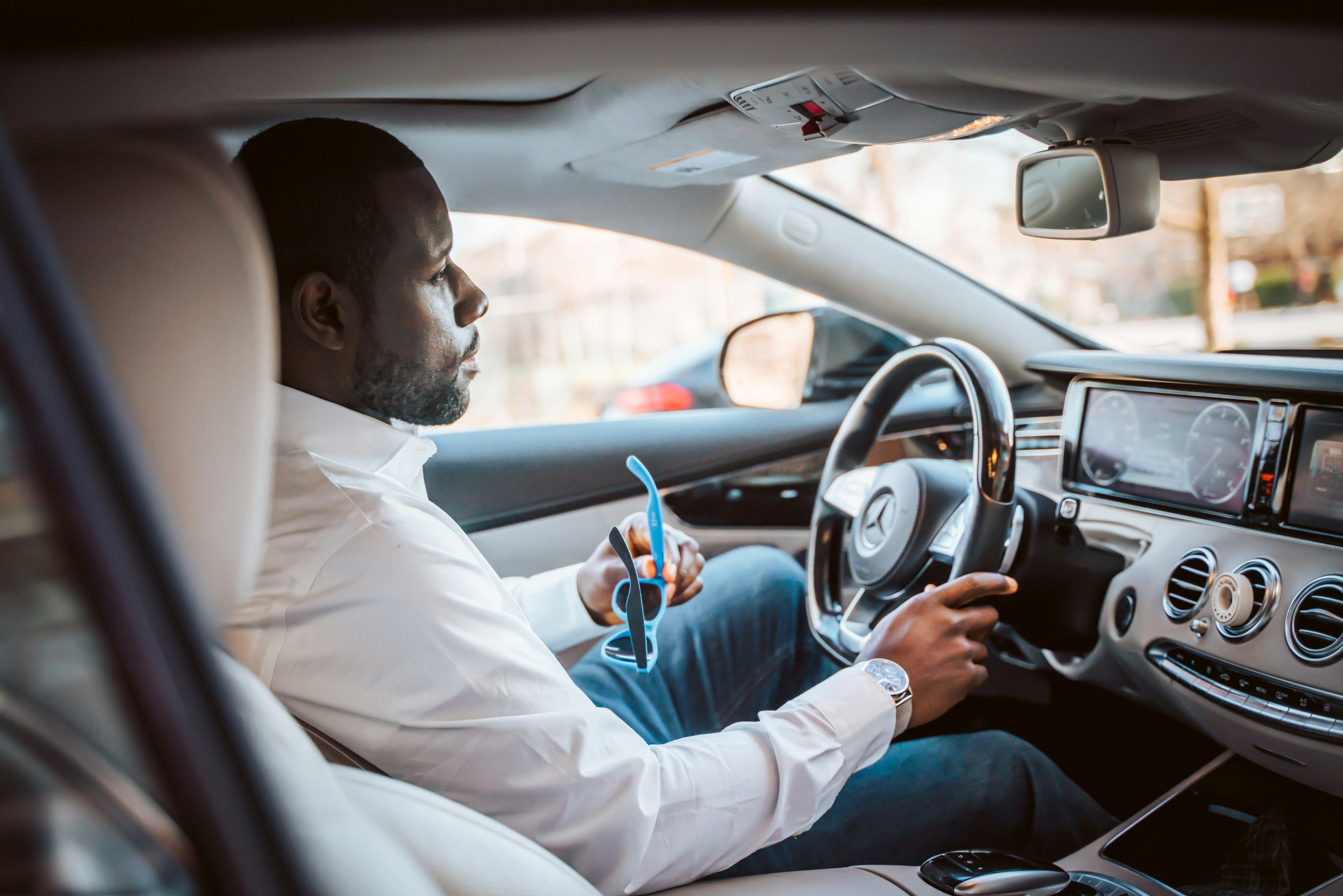 black man in business attire driving car